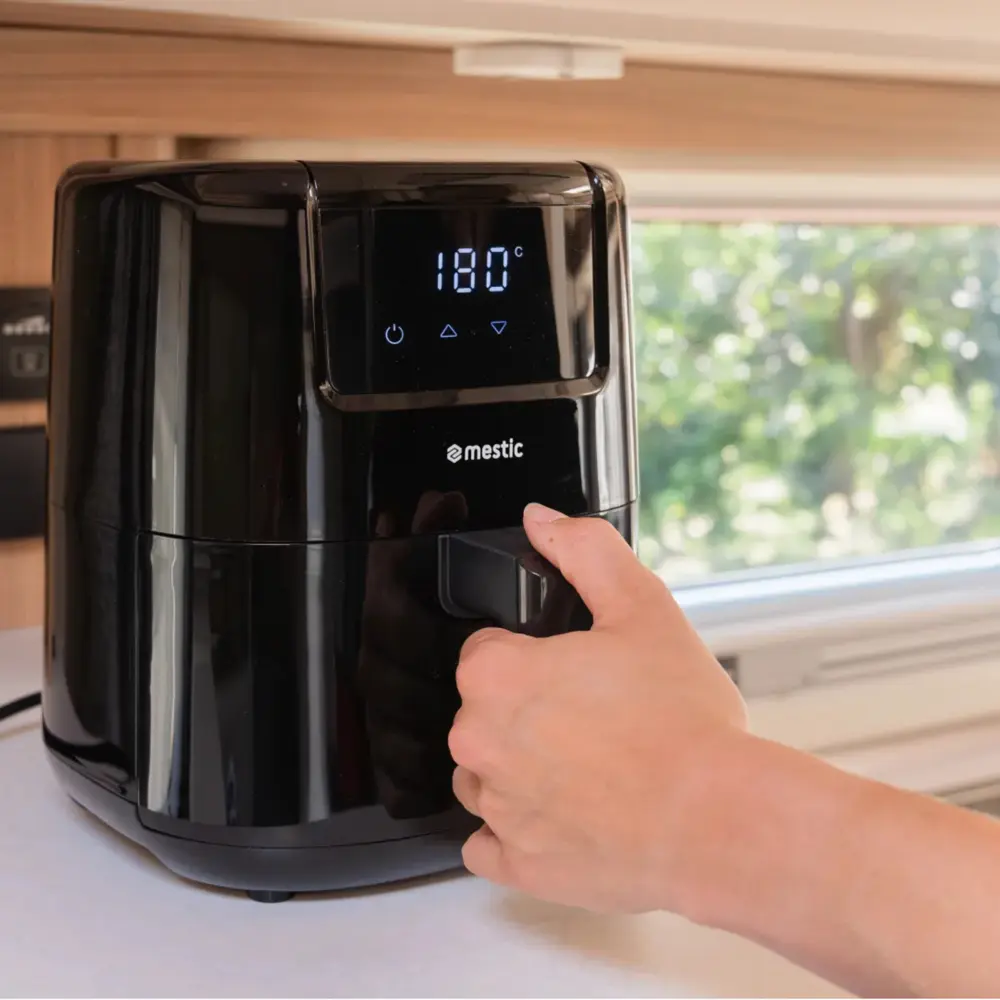 mestic-ma-300-airfryer-im-wohnmobil Mestic Airfryer MA-300 auf der Arbeitsplatte einer Wohnmobilküche, eine Hand öffnet die Schublade